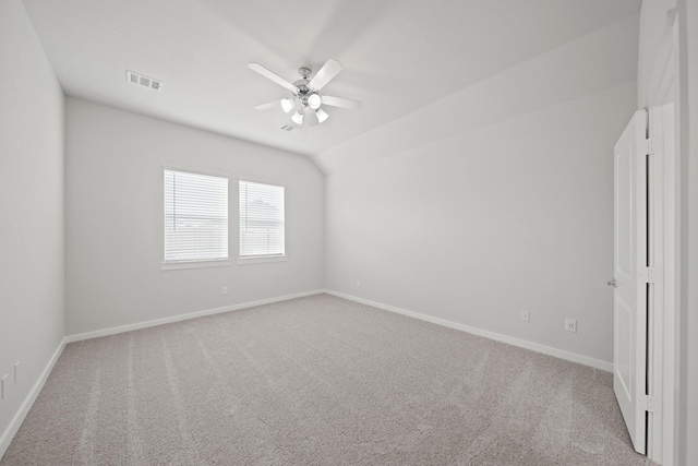 carpeted empty room featuring visible vents, lofted ceiling, baseboards, and a ceiling fan