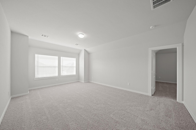 spare room featuring vaulted ceiling, baseboards, visible vents, and carpet floors