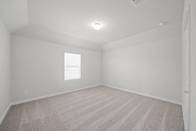 empty room with lofted ceiling, carpet flooring, visible vents, and baseboards