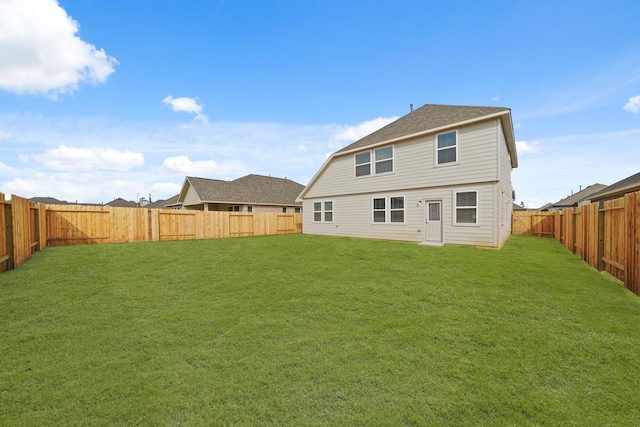 back of house featuring a fenced backyard, a yard, and roof with shingles