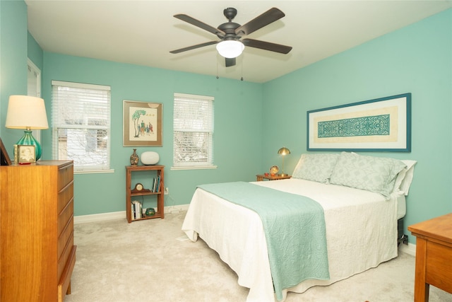 bedroom with ceiling fan, light colored carpet, and multiple windows