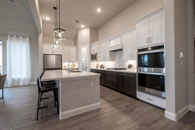 kitchen with visible vents, custom range hood, a sink, stainless steel appliances, and backsplash