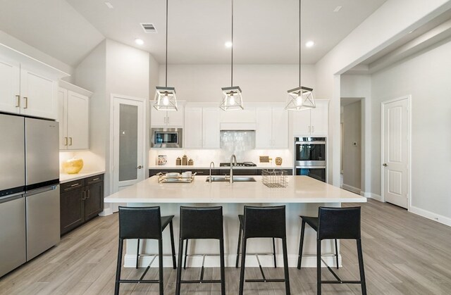 kitchen with visible vents, a high ceiling, appliances with stainless steel finishes, and a breakfast bar area