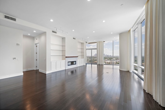 unfurnished living room with dark wood-type flooring, built in features, and a wall of windows