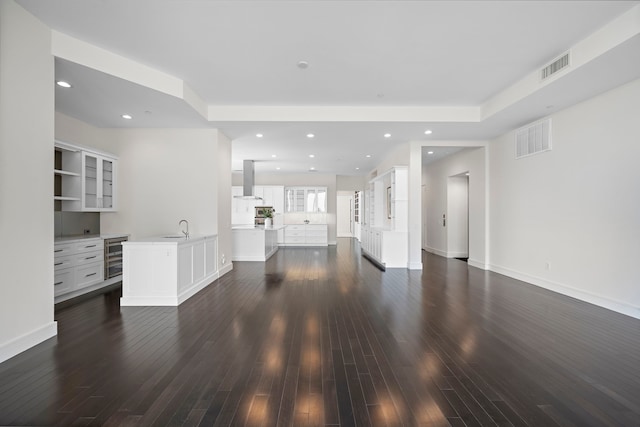 unfurnished living room featuring dark hardwood / wood-style floors, sink, and wine cooler