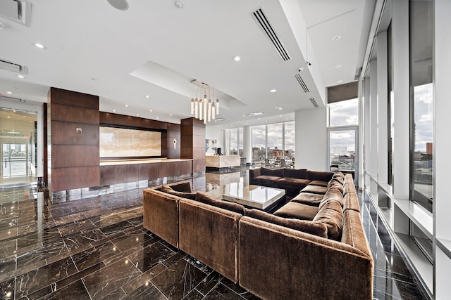 living room with a wealth of natural light, a raised ceiling, and a wall of windows