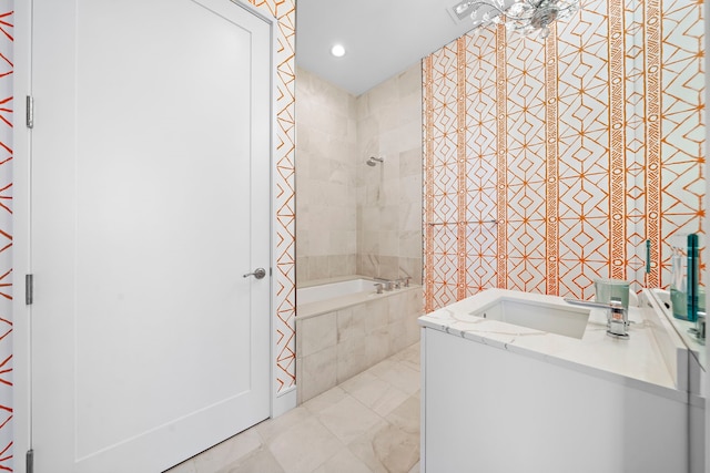 bathroom with tiled shower / bath, vanity, and tile walls