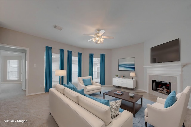 living room featuring light carpet, a tile fireplace, and ceiling fan