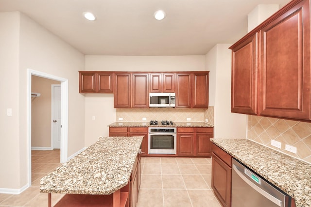 kitchen featuring light stone counters, tasteful backsplash, light tile patterned flooring, and appliances with stainless steel finishes