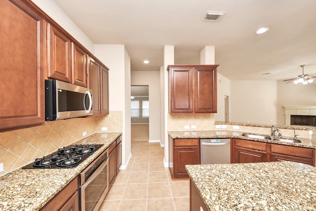 kitchen featuring light stone counters, sink, light tile patterned floors, and stainless steel appliances