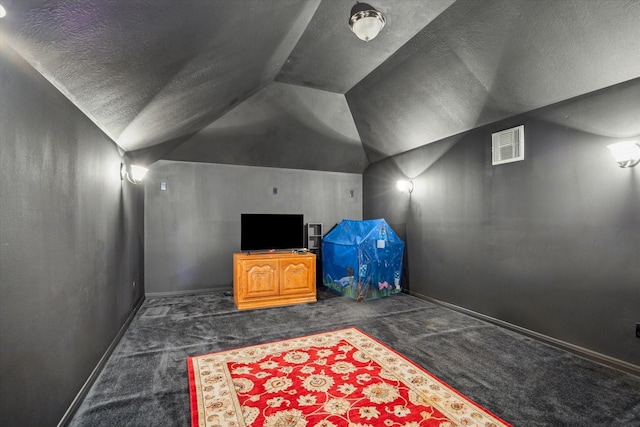 cinema room featuring lofted ceiling, a textured ceiling, and dark colored carpet