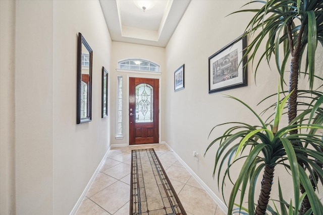 foyer entrance with light tile patterned floors and a tray ceiling