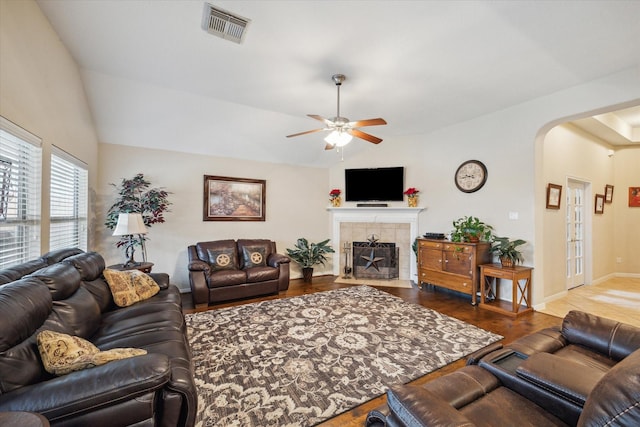 living room featuring lofted ceiling, a tiled fireplace, dark hardwood / wood-style flooring, and ceiling fan