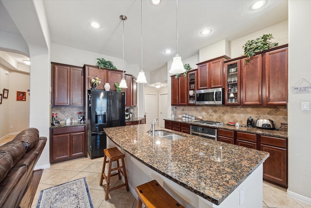 kitchen with sink, stainless steel appliances, hanging light fixtures, and a center island with sink