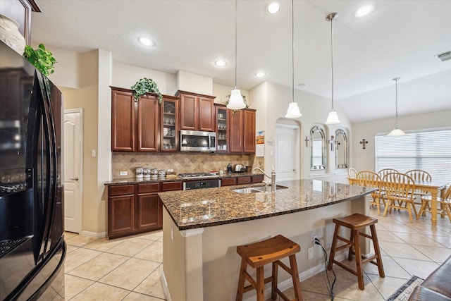 kitchen with sink, tasteful backsplash, dark stone counters, pendant lighting, and stainless steel appliances