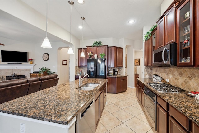 kitchen with sink, appliances with stainless steel finishes, a kitchen island with sink, tasteful backsplash, and decorative light fixtures