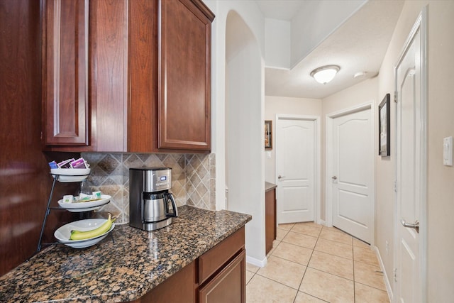 kitchen featuring tasteful backsplash, dark stone countertops, and light tile patterned floors