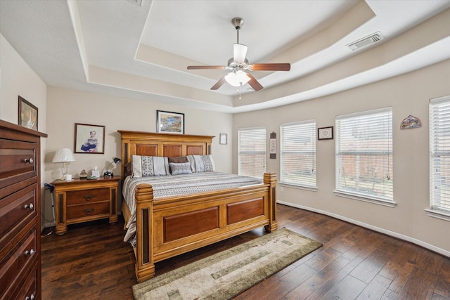 bedroom with a raised ceiling, dark hardwood / wood-style floors, and ceiling fan