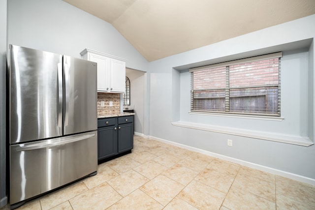 kitchen featuring lofted ceiling, white cabinetry, tasteful backsplash, light tile patterned floors, and stainless steel refrigerator