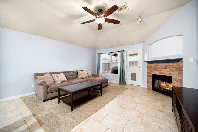 tiled living room with ceiling fan, a stone fireplace, and vaulted ceiling