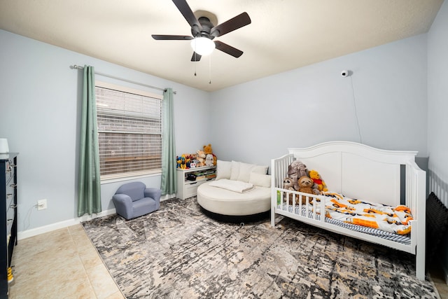 tiled bedroom with a crib and ceiling fan