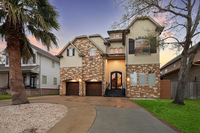 view of front of property with stucco siding, french doors, a garage, a balcony, and driveway