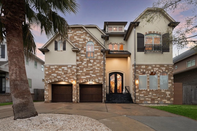 view of front of home with concrete driveway, french doors, stone siding, and stucco siding