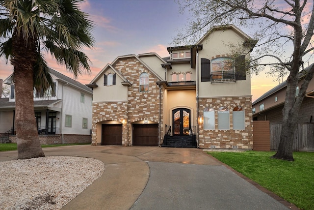 view of front of property featuring a balcony, french doors, driveway, and stucco siding