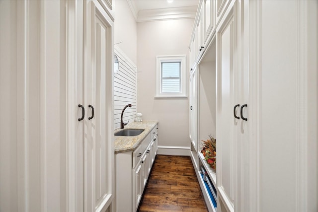 mudroom featuring crown molding, baseboards, dark wood-style flooring, and a sink