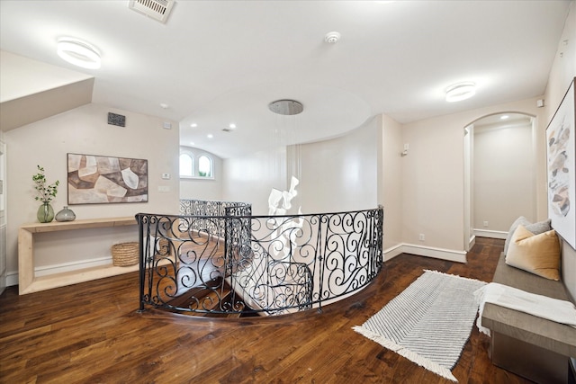 hallway with wood finished floors, an upstairs landing, visible vents, and vaulted ceiling