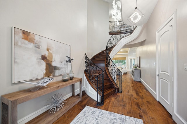 staircase featuring a high ceiling, baseboards, and hardwood / wood-style floors