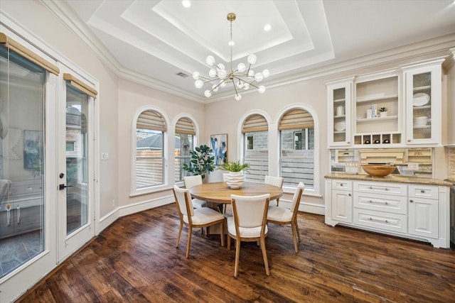 dining room with a tray ceiling, an inviting chandelier, dark wood-style floors, and visible vents