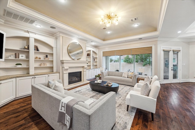 living room featuring visible vents, dark wood-type flooring, and a tray ceiling