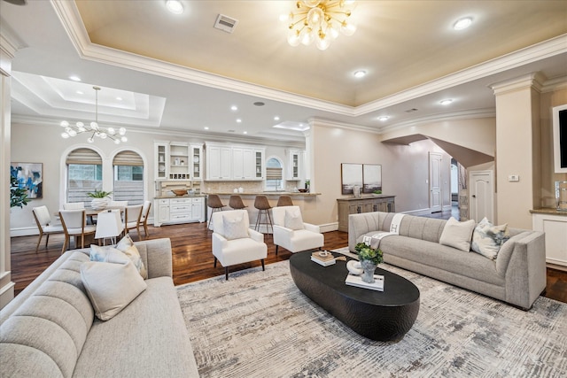 living area featuring visible vents, dark wood-type flooring, arched walkways, an inviting chandelier, and a raised ceiling