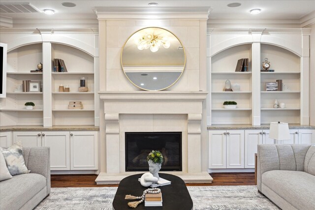 living area featuring visible vents, a fireplace with raised hearth, dark wood-style flooring, and ornamental molding