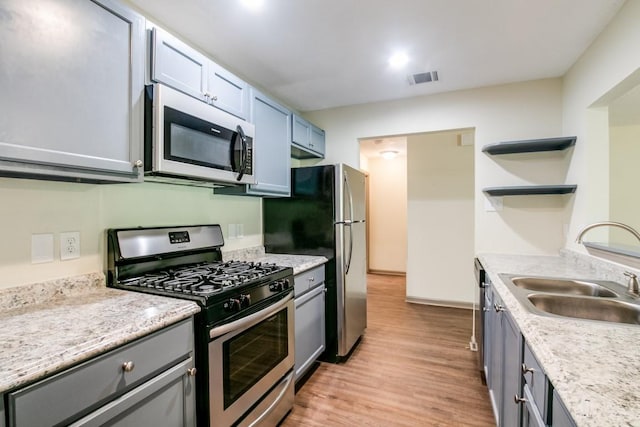 kitchen with sink, light hardwood / wood-style floors, light stone countertops, and appliances with stainless steel finishes