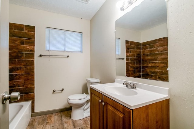 full bathroom featuring washtub / shower combination, toilet, a textured ceiling, vanity, and hardwood / wood-style floors