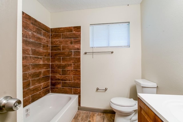 full bathroom featuring toilet, a textured ceiling, vanity, tiled shower / bath combo, and hardwood / wood-style floors