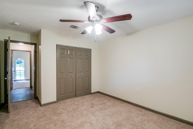 unfurnished bedroom with light colored carpet, ceiling fan, and a closet