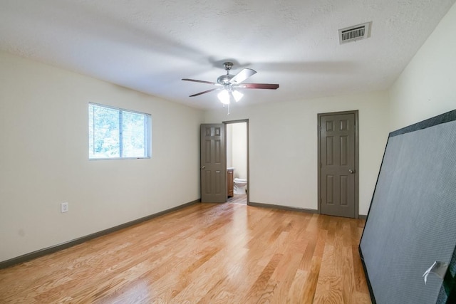 unfurnished bedroom with ceiling fan, ensuite bath, light hardwood / wood-style flooring, and a textured ceiling