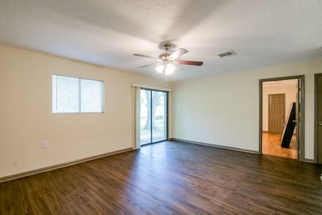 empty room with ceiling fan, dark wood-type flooring, and a textured ceiling