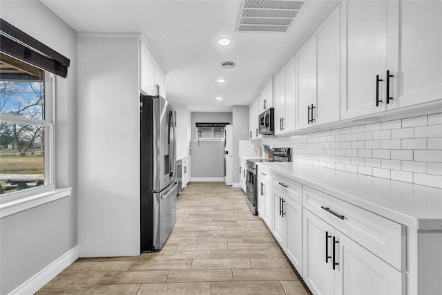 kitchen featuring tasteful backsplash, stainless steel appliances, light stone counters, and white cabinets