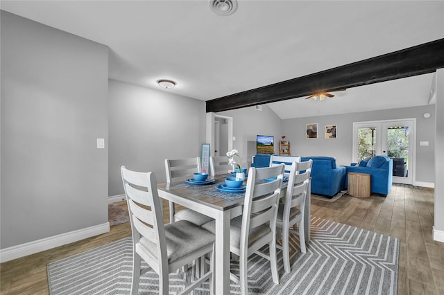 dining space featuring wood-type flooring, vaulted ceiling with beams, and french doors