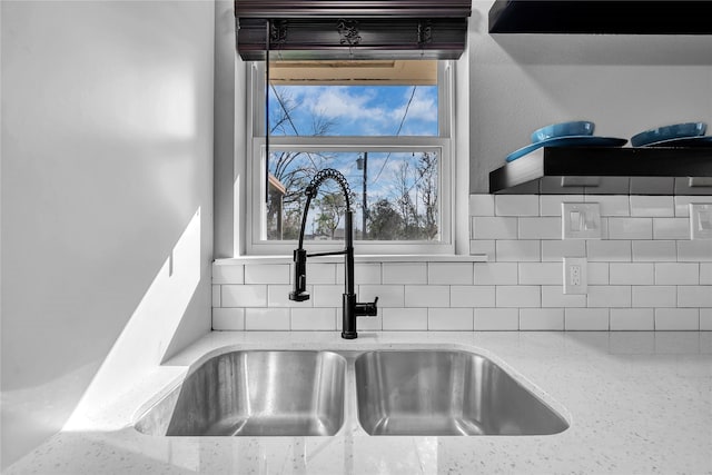 details featuring tasteful backsplash, sink, and light stone countertops