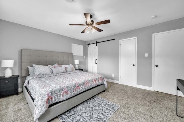 bedroom with ceiling fan, light colored carpet, and a barn door