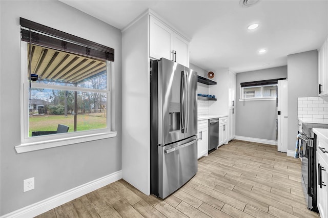 kitchen with stainless steel appliances, white cabinets, and light wood-type flooring