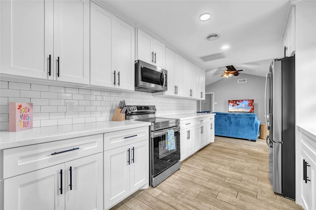 kitchen with vaulted ceiling, white cabinetry, ceiling fan, stainless steel appliances, and light hardwood / wood-style flooring