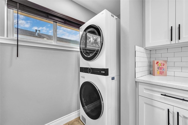 washroom with cabinets and stacked washer / drying machine