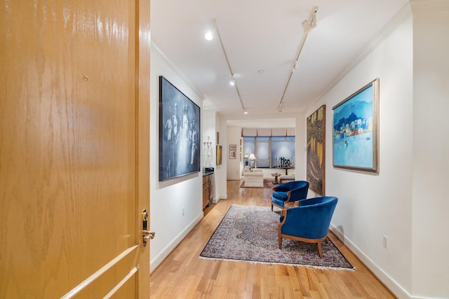 hall with rail lighting, crown molding, and light hardwood / wood-style flooring