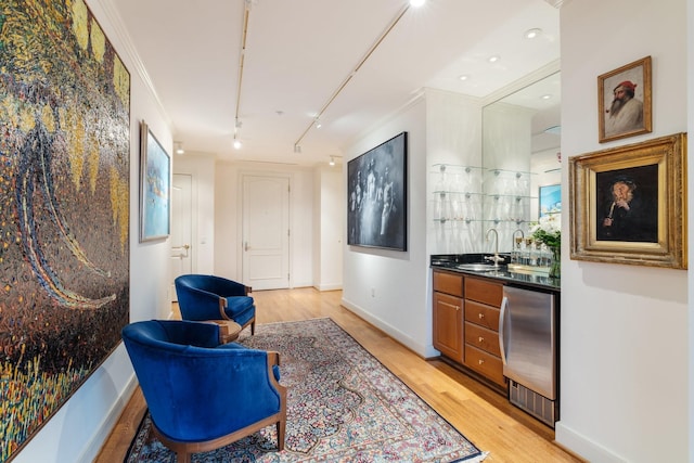 interior space with rail lighting, sink, light wood-type flooring, ornamental molding, and stainless steel fridge